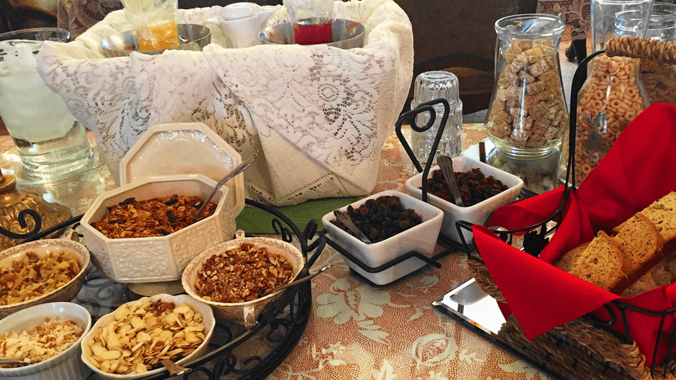 A beautifully arranged breakfast buffet featuring various granola, nuts, dried fruits, and bread.